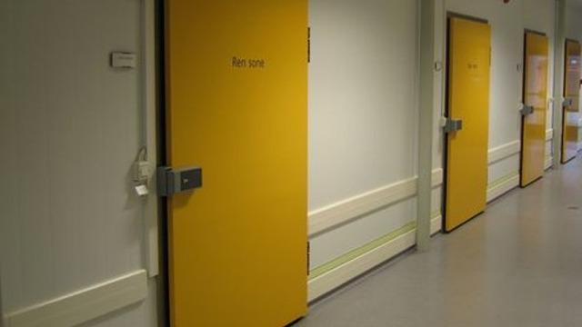 Gule dører i en korridor med nummererte rom i en moderne bygning.
