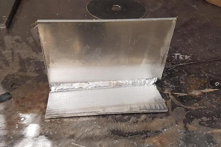 Sveiset aluminiumsplate med jevn overflate og tydelig sveisesøm på arbeidsbenk.