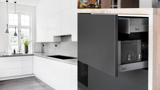 Moderne kjøkken med hvite skap, svart kjøleskap og åpnet skuff med glass og servise.