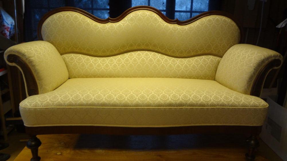 En elegant sofa med bølget rygg og mønstrete stoff, plassert i et rom med naturlig lys.