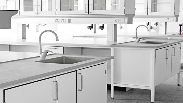 Moderne laboratoriemiljø med hvite benker og vasker, godt opplyst og ryddig.