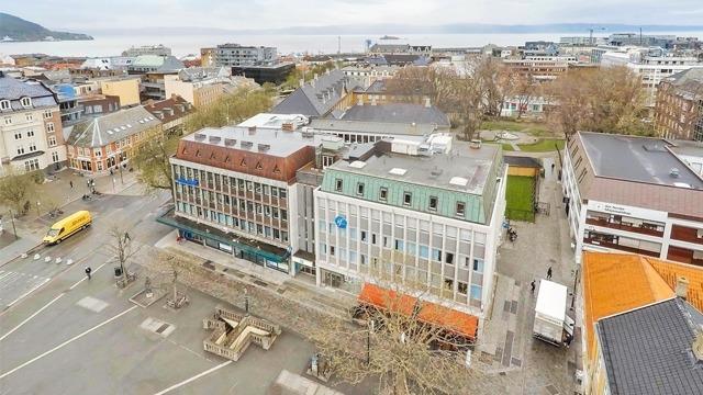 Oversiktsbilde av en bygate med moderne bygninger, parker og biler i nærheten av vannet.