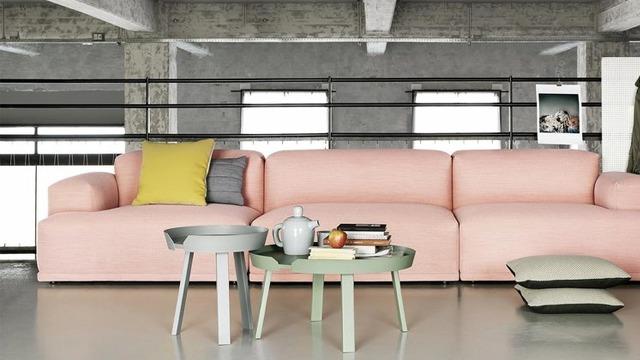 Moderne stue med en rosa sofa, et grønt bord, en tepotte og puter i en lys, minimalistisk innredning.