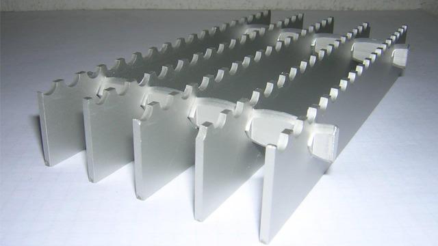 Aluminiumprofiler med spor for montering, plassert i en rekke på hvit bakgrunn.