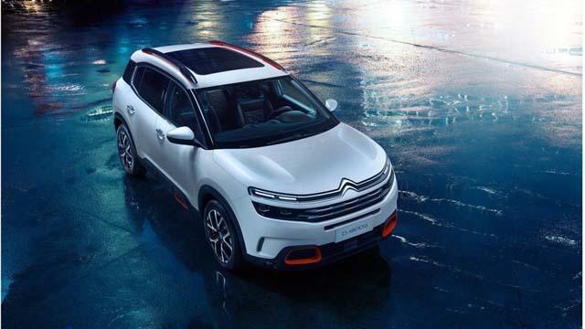 En moderne SUV fra Citroën parkert på en våt gate om natten, med refleksjoner fra lysene rundt.