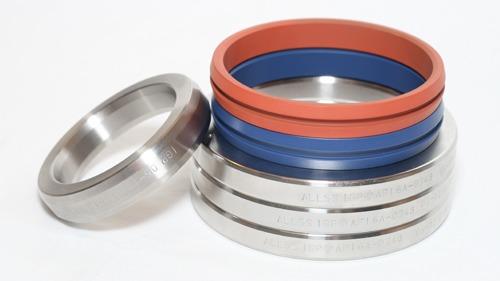 En stabel med metallringer og fargede gummiringer i blått, rødt og svart på en hvit bakgrunn.