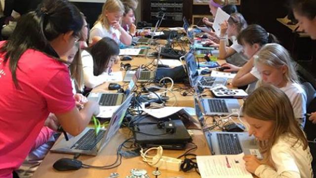 Jenter som deltar i en datakurs, arbeider med bærbare datamaskiner og programmeringsprosjekter.