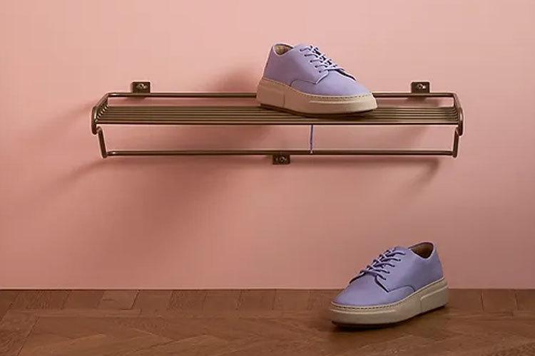 Lilla sneakers på en moderne sko hylle mot en rosa vegg.