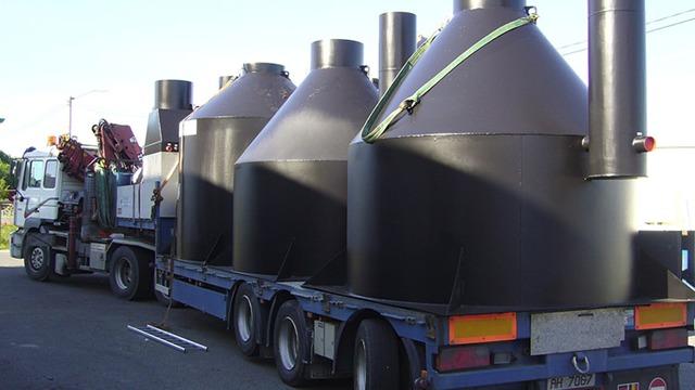 Tre store svarte tanker på en lastebil, klar for transport.