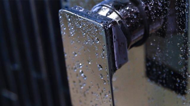Vannperler på en blank, metallisk overflate av en dørhåndtak.