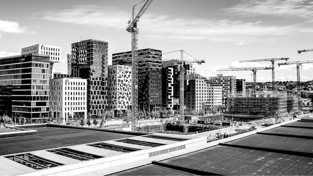 Moderne bygninger og kraner i et bylandskap under utvikling, svart-hvitt bilde av urban arkitektur.