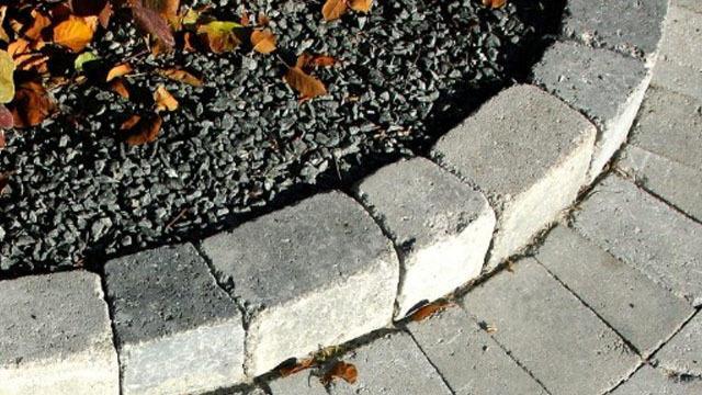 En rund kant av steinblokker som omkranser en hage med grus og høstblader.