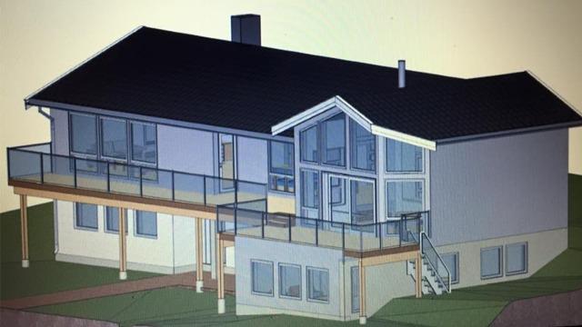 Moderne hus med stor terrasse, glassvinduer og skråtak, plassert på en skråning.