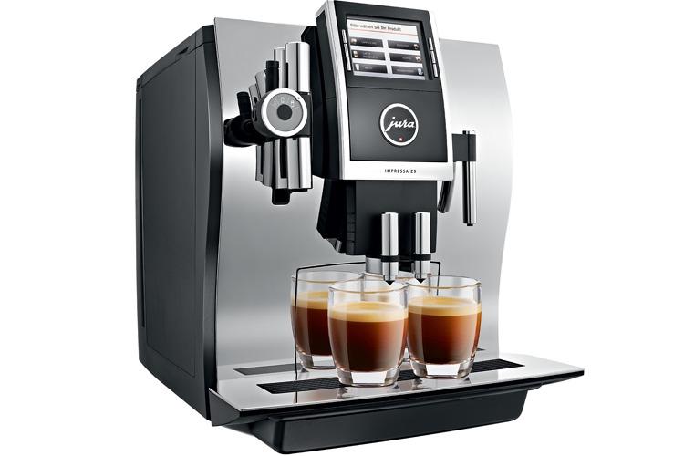 Kaffemaskin med tre glass espresso på en moderne benk, med blankt metall og stilrent design.
