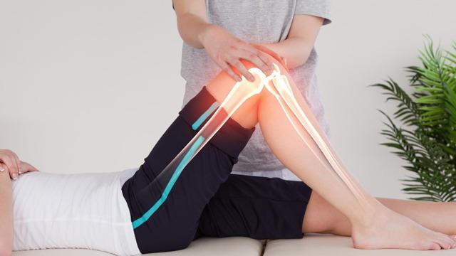 En fysioterapeut behandler en pasient med kneproblemer, med fokus på kneleddet og bevegelse.