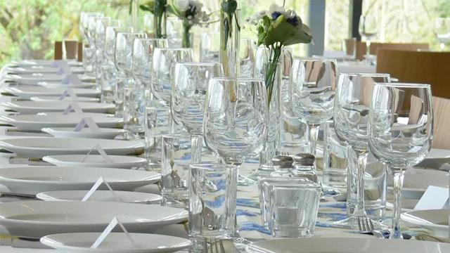 Et elegant dekket bord med glass og tallerkener, dekorert med blomster i en moderne restaurant.