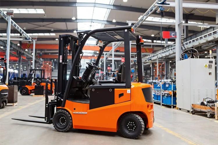 En oransje gaffeltruck står i en lagerhall med moderne utstyr og belysning.