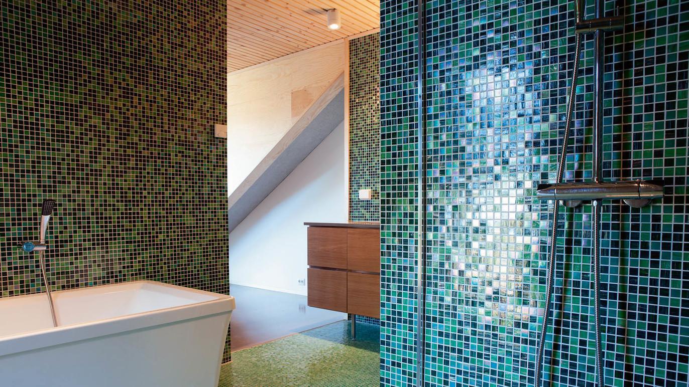 Moderne bad med mosaikkfliser i grønt og blått, badekar og dusj med stilren innredning.
