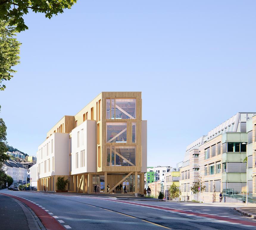 Moderne trebygning med store vinduer, beliggende langs en gate med moderne kontorbygg i bakgrunnen.
