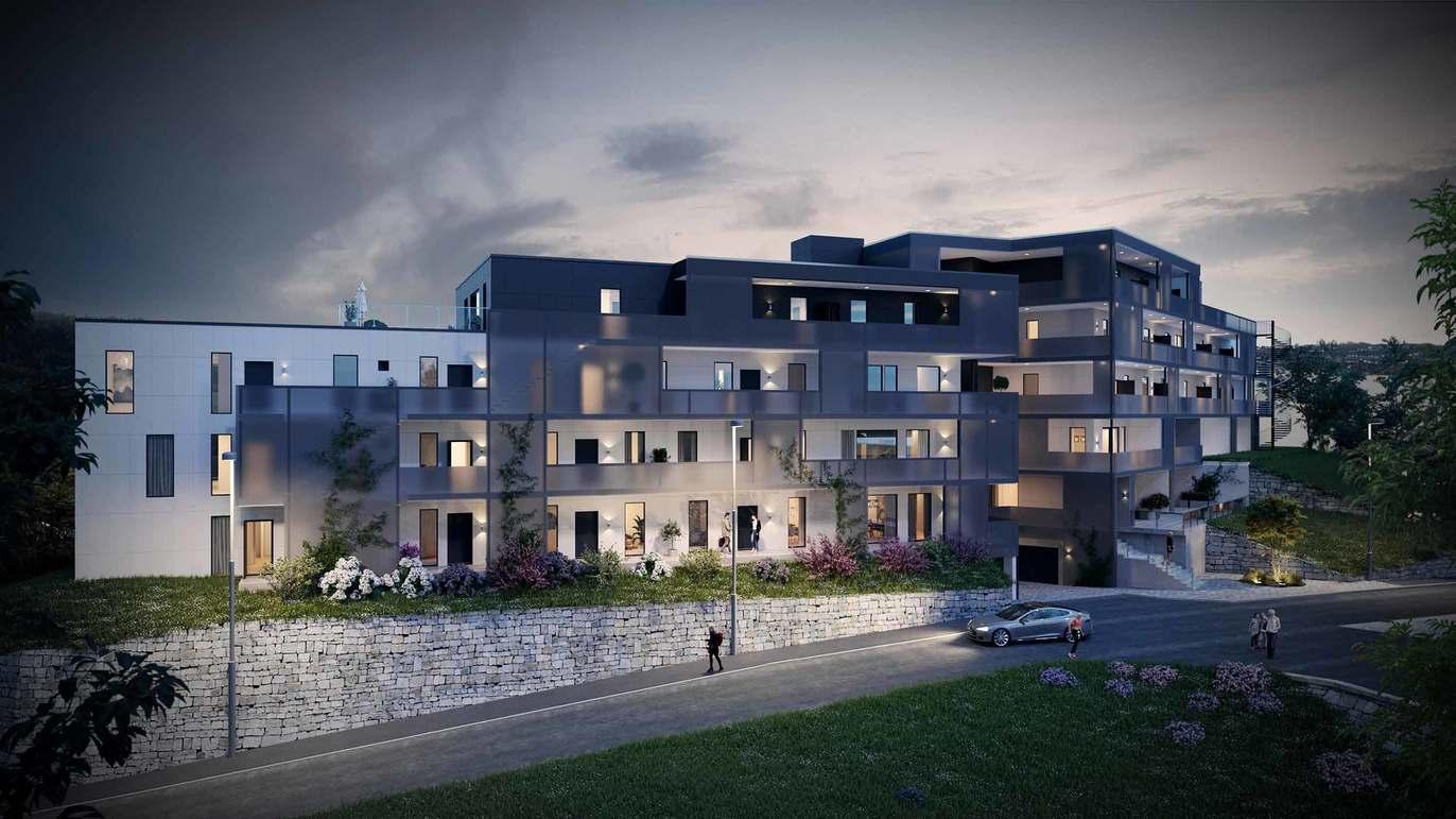 Moderne leilighetskompleks med balkonger og hage, beliggende ved en vei i naturskjønt område.