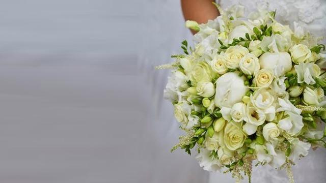 En brud med en vakker bukett av hvite roser og blomster i pastellfarger.
