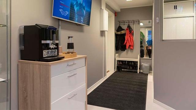 En moderne gang med en kaffemaskin, TV på veggen, og oppbevaringsskap for klær og sko.