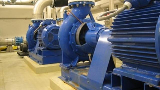Blå pumper og motorer i en industriell anlegg, plassert på betonggulv.