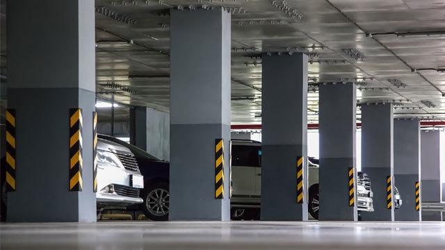 Parkering med flere biler og søyler i en moderne parkeringskjeller. Søyler har gule og svarte striper.