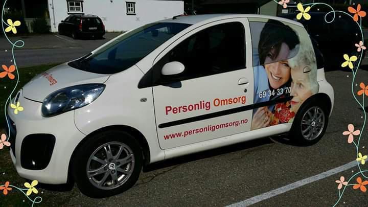 En hvit bil med reklame for "Personlig Omsorg" og bilder av mennesker på siden.
