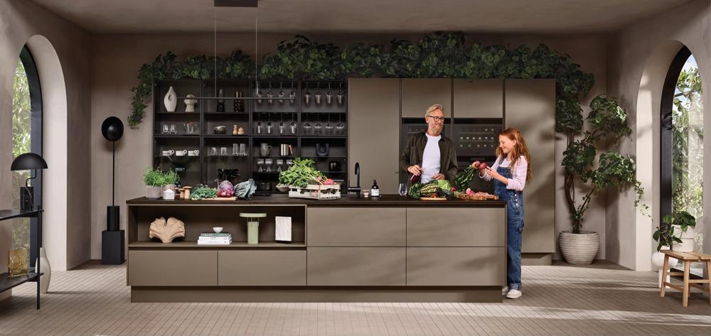 Moderne kjøkken med en voksen og et barn som lager mat sammen, omringet av planter og stilige kjøkkenredskaper.