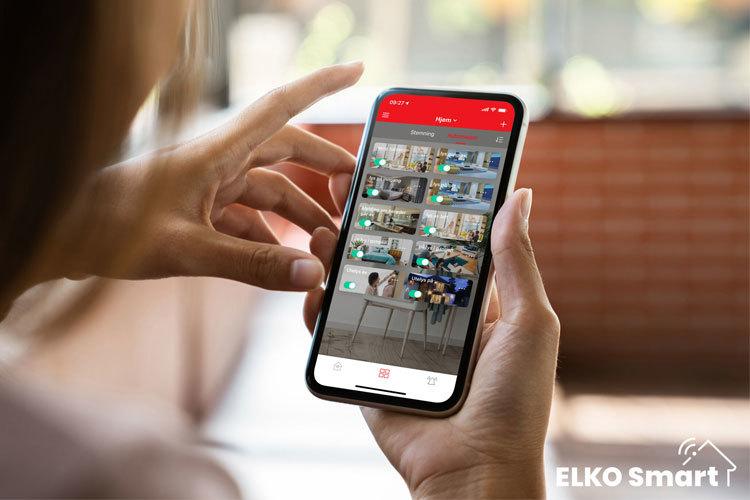 En person som bruker en smarttelefon med ELKO Smart-appen å styre hjemmet sitt.