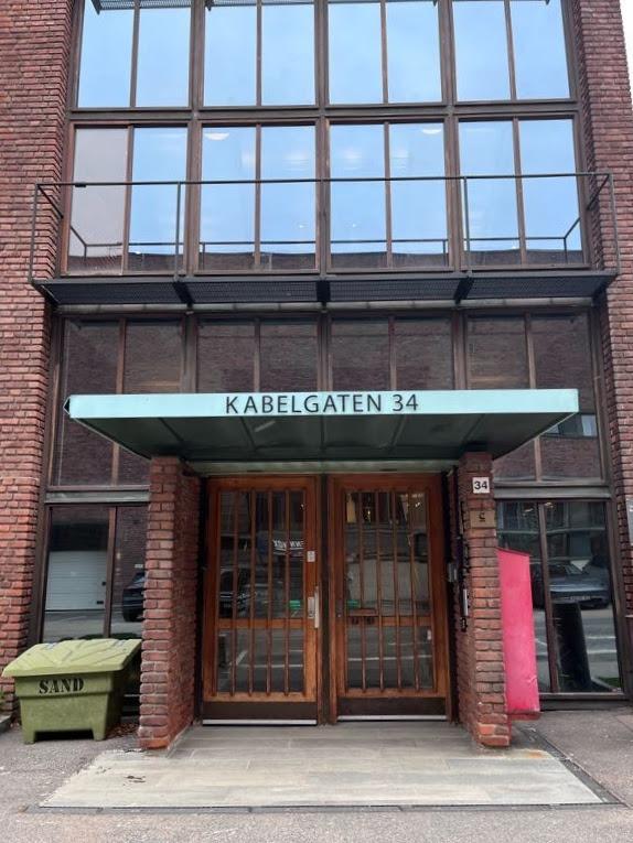 Inngangspartiet til Kabelgaten 34 med store vinduer og en grønn takoverbygg.