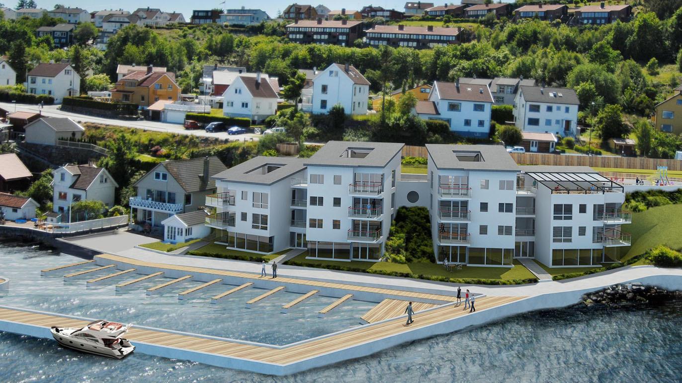 Moderne leiligheter ved sjøen med båtplasser, omgitt av grønne områder og boliger i bakgrunnen.