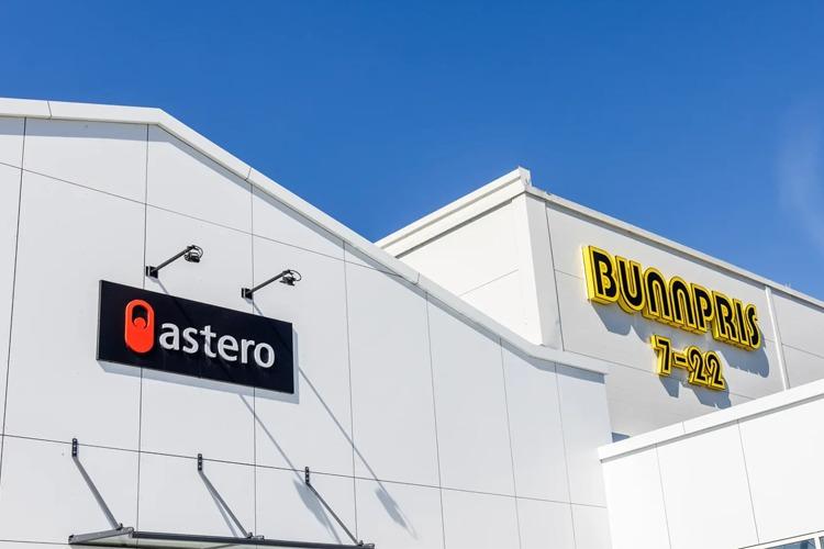 Logoene til Astero og Bunnpris på en moderne butikkfasade under blå himmel.