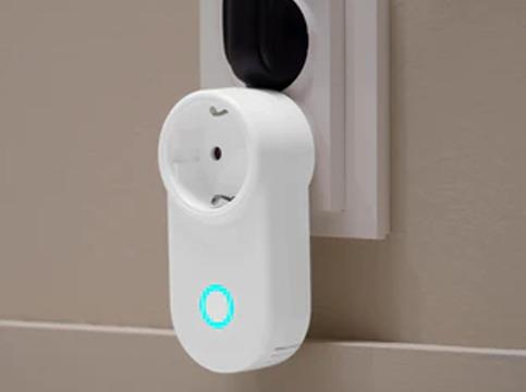 En hvit smartplugg koblet til en stikkontakt med et blått lys som indikerer tilkobling.