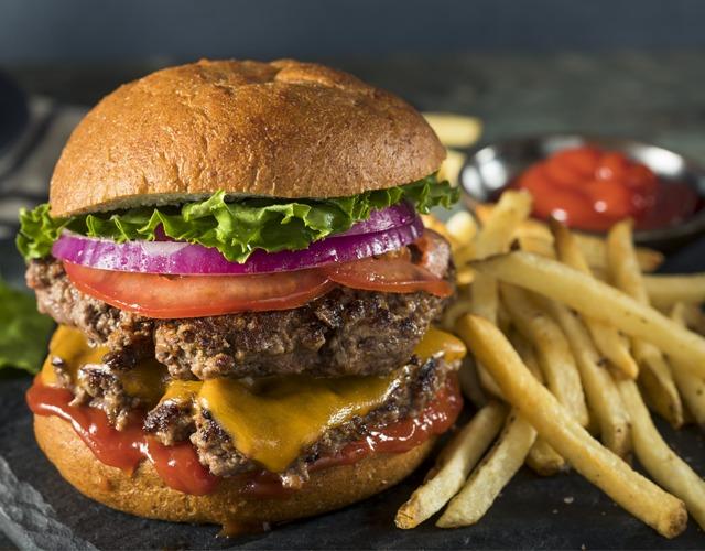 Saftig hamburger med cheddarost, salat, tomat og rødløk, servert med pommes frites og ketchup.