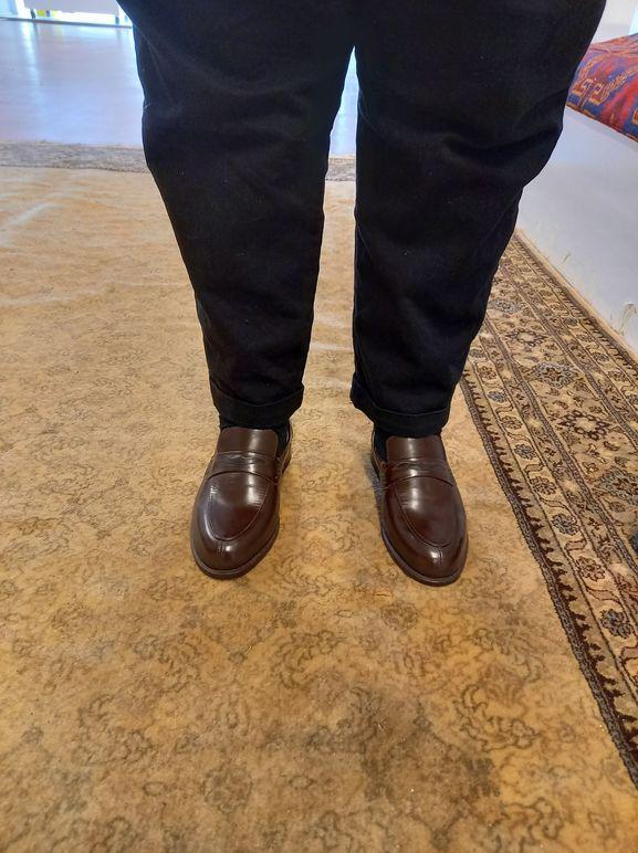 Brune dressko på en person som står på et teppe i et rom.