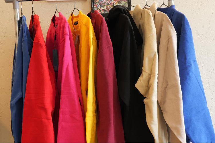 Fargerike jakker i forskjellige nyanser henger på en kleshenger, inkludert rød, rosa, gul, burgunder, svart, beige og blå.