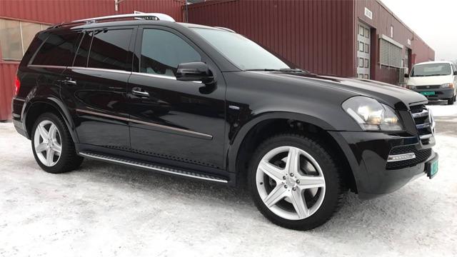 Svart SUV parkert på snø, med moderne design og store felger, foran en rød bygning.