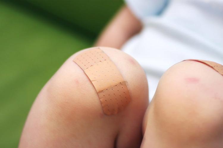 Et nærbilde av et barns knær med plaster på begge knærne etter å ha fått skrubbsår.
