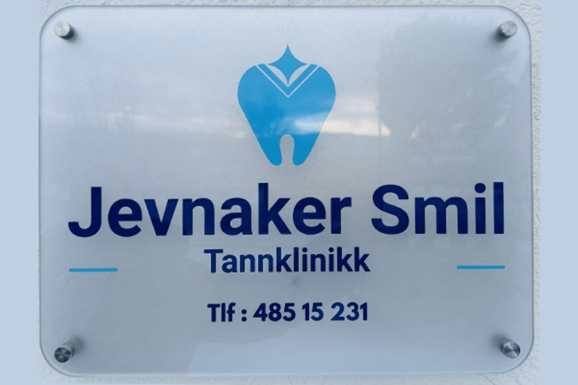 Skilt for Jevnaker Smil tannklinikk med logo og kontaktinformasjon.
