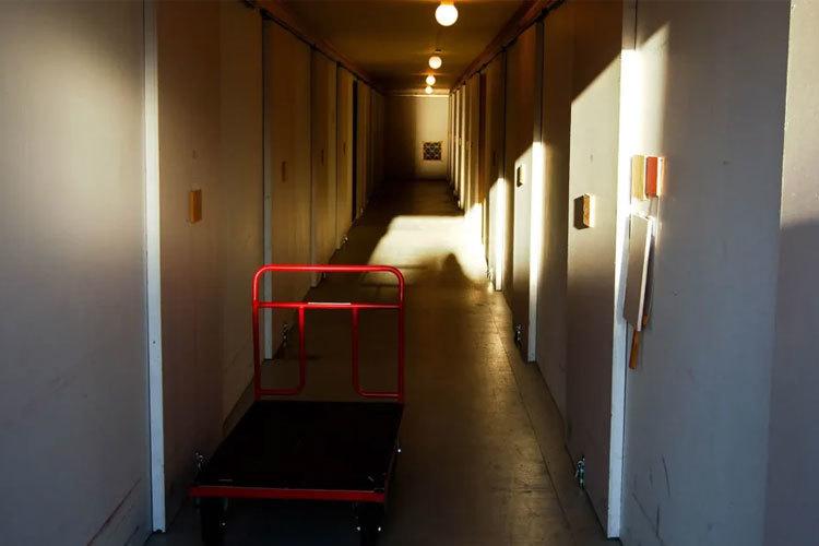 En lang korridor med lys, en rød tralle står på gulvet mellom veggene.