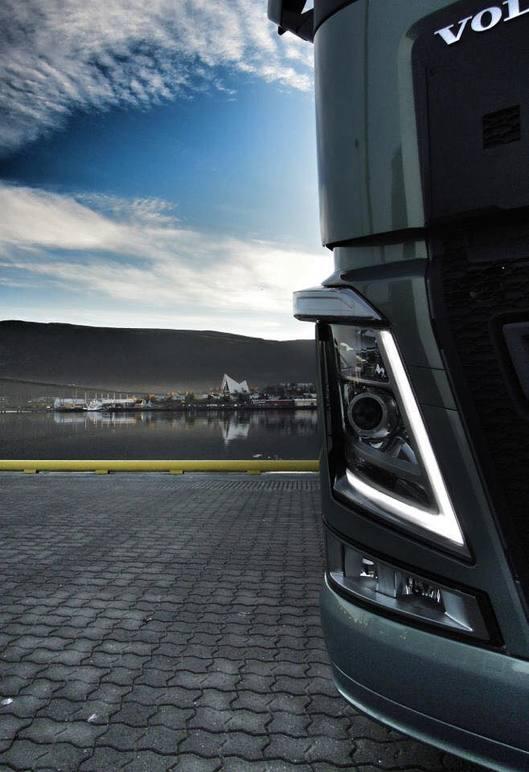 Volvo lastebil med moderne frontdesign, stående ved en innsjø under en klar himmel.