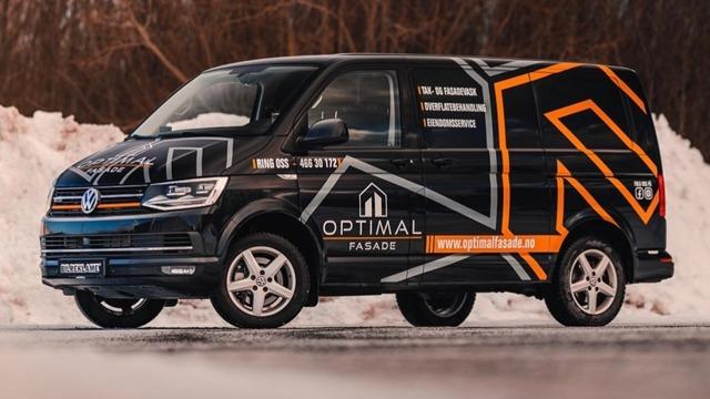 En svart Volkswagen varebil med Optimal Fasade-logo og grafisk design står på en snødekt vei.