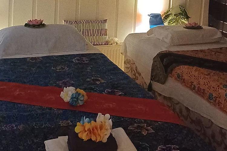 To rom med senger dekorert med blomster og fargerike tekstiler i et koselig miljø.