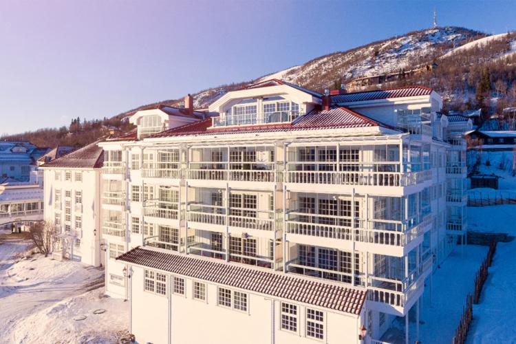 Moderne hotellbygning med store vinduer, beliggende i snødekt fjellandskap.