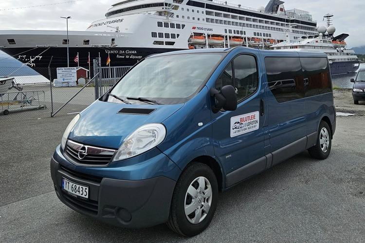 Blå varebil parkert foran et cruiseskip i havnen, med skilt på siden som viser leietjeneste.