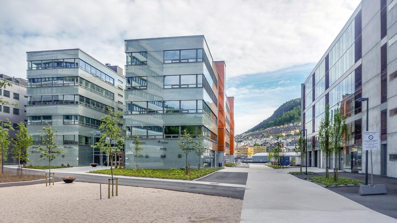 Moderne bygninger med glassfasader og grønne områder i en bygate i Bergen.