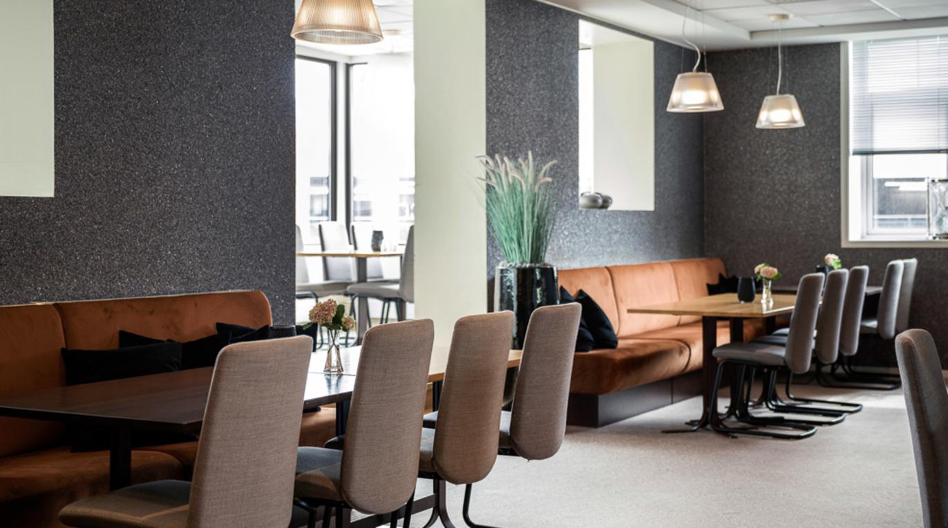 Moderne restaurantinteriør med brune sitteplasser, bord og stilige lamper i et lyst rom.