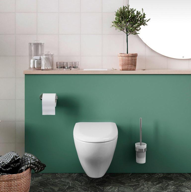 Moderne toalett med grønn vegg, speil, planter og toalettpapirholder i et stilrent baderom.
